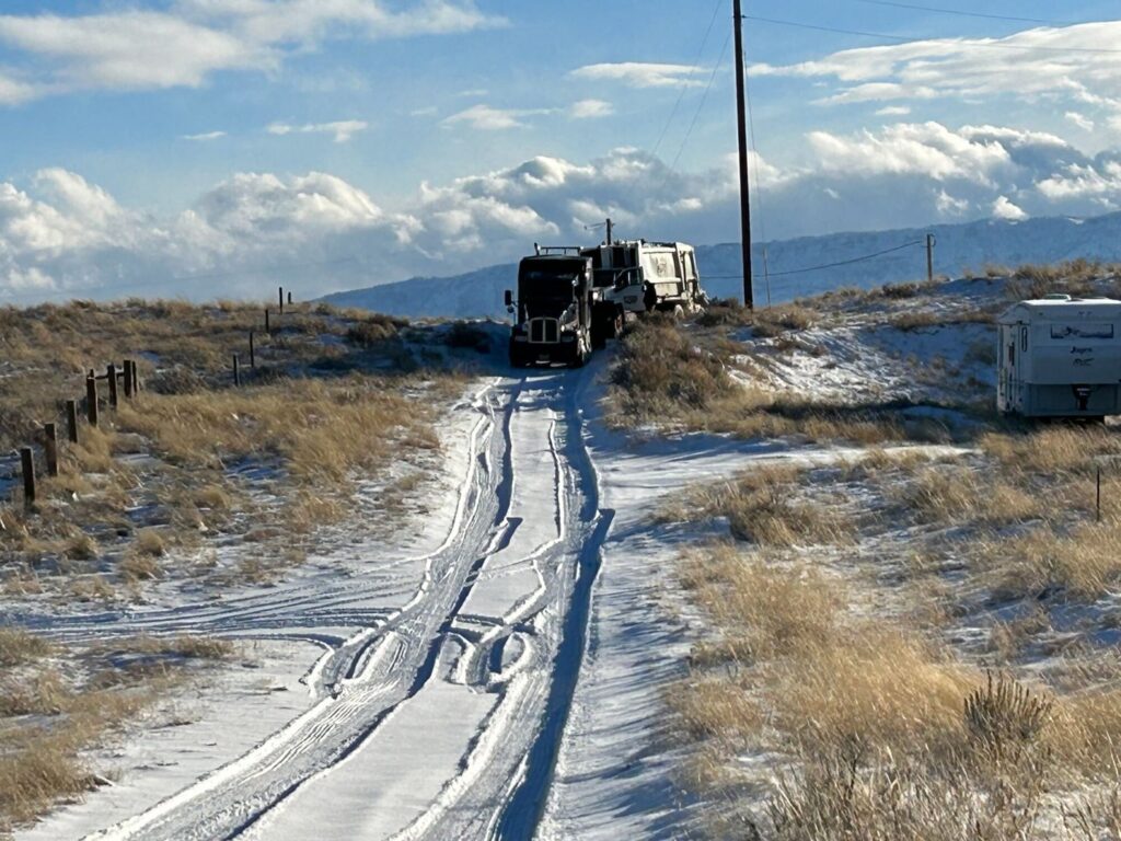 A heavy-duty tow truck from Select Towing and Recovery pulling a semi-truck up a snowy incline in Casper, WY.