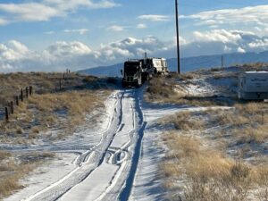 A heavy-duty tow truck from Select Towing and Recovery pulling a semi-truck up a snowy incline in Casper, WY.