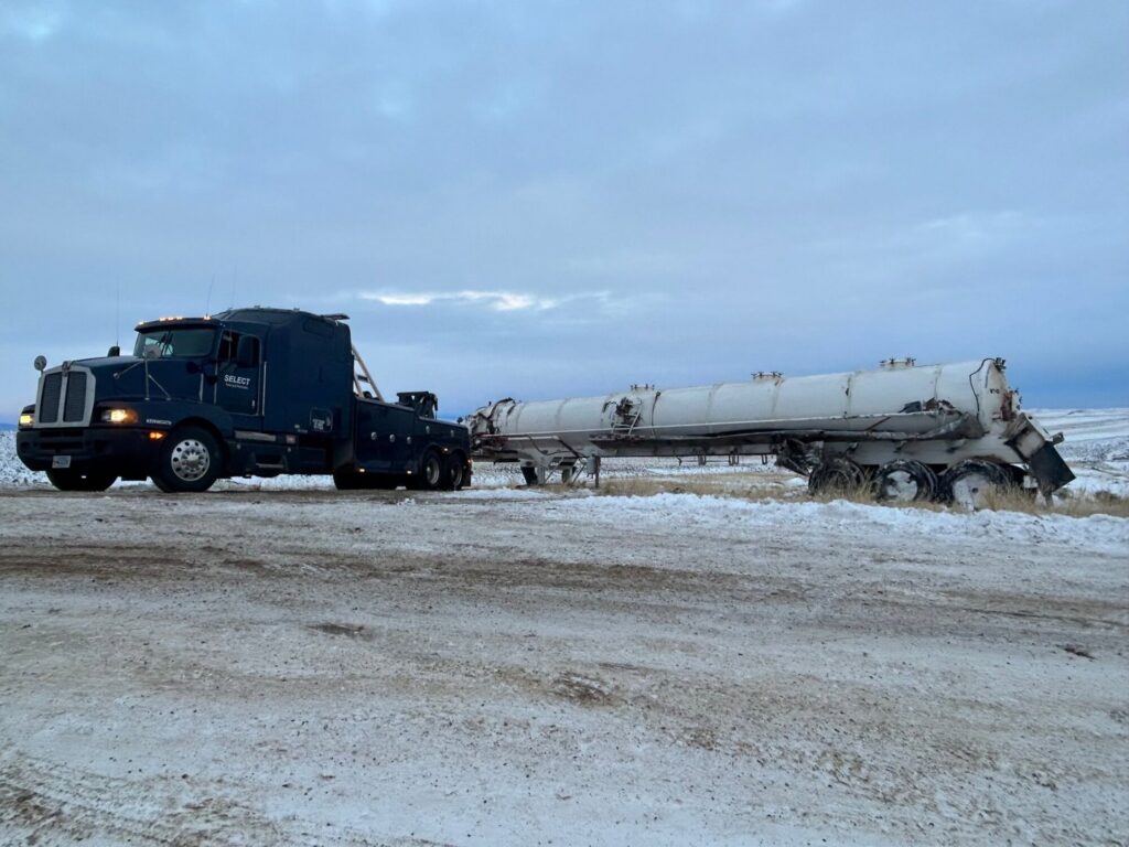 A heavy-duty tow truck from Select Towing and Recovery recovering a damaged tanker trailer from a ditch in Casper, WY.