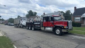 A heavy-duty tow truck from Sawyer Towing is actively towing a large dump truck in Cincinnati, OH.