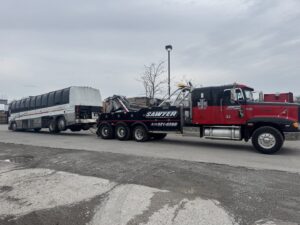 A heavy-duty tow truck from Sawyer Towing is actively towing a large passenger bus in Cincinnati, OH.
