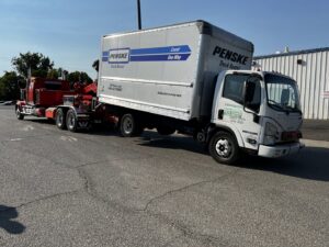 A red heavy-duty tow truck from Anthony's Towing & Transportation towing a Penske rental truck in Yuba City, CA.