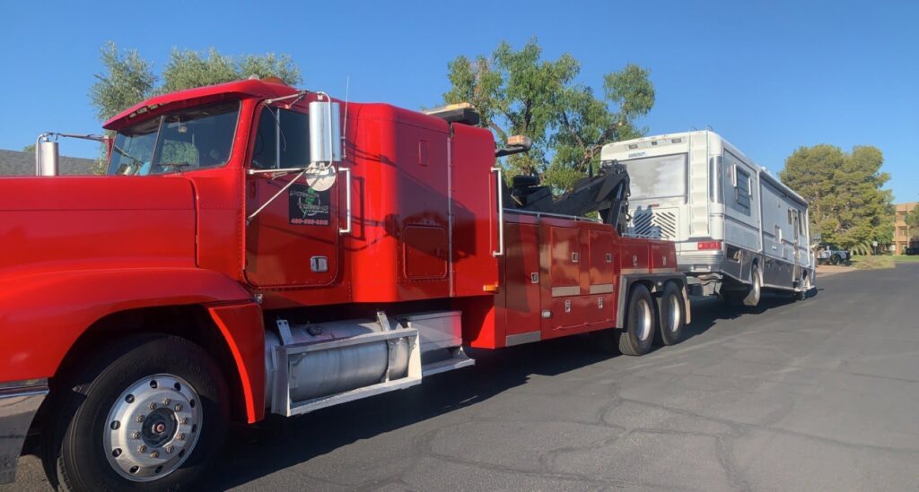 A red heavy-duty tow truck from Power Towing & Transport towing a large RV or motorhome in Phoenix, AZ.
