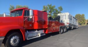 A red heavy-duty tow truck from Power Towing & Transport towing a large RV or motorhome in Phoenix, AZ.