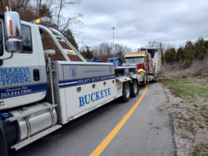 A Buckeye Riverside Towing heavy-duty tow truck assisting a semi-truck in Cincinnati, OH.