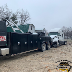 A heavy-duty tow truck from Sunny Acres Towing towing a semi-truck cab in Greenville, IN.