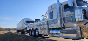 A McDowell Wrecker Service heavy-duty tow truck towing a semi-truck on a highway in Springfield, MO.