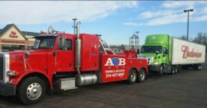 A heavy-duty tow truck from A2B Towing & Recovery towing a green semi-truck in Hazelwood, MO.
