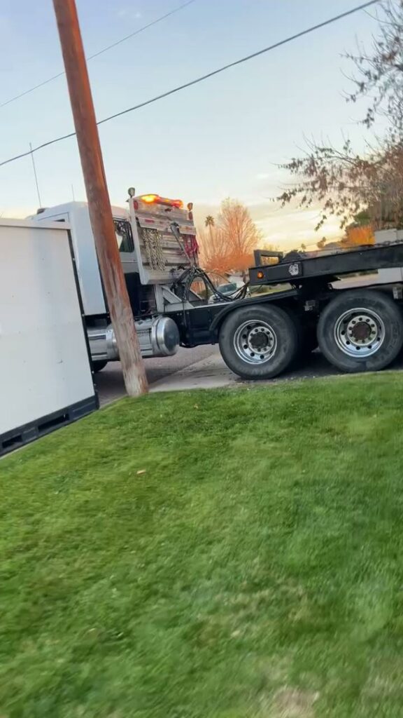 A heavy-duty tow truck from Power Towing & Transport towing a large white box trailer in Phoenix, AZ.