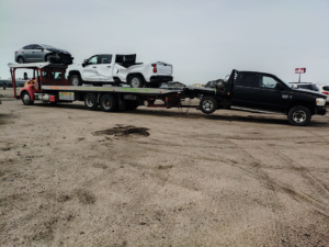A heavy-duty car carrier truck from Rivera Garcia Towing transporting a pickup and towing another in Omaha, NE.