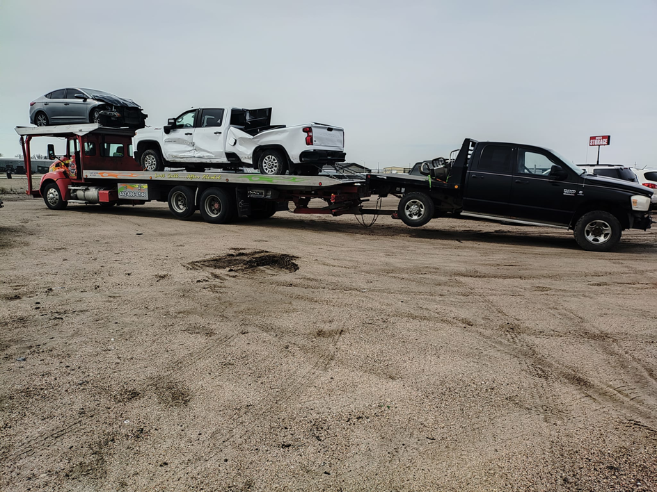 A heavy-duty car carrier truck from Rivera Garcia Towing transporting a pickup and towing another in Omaha, NE.