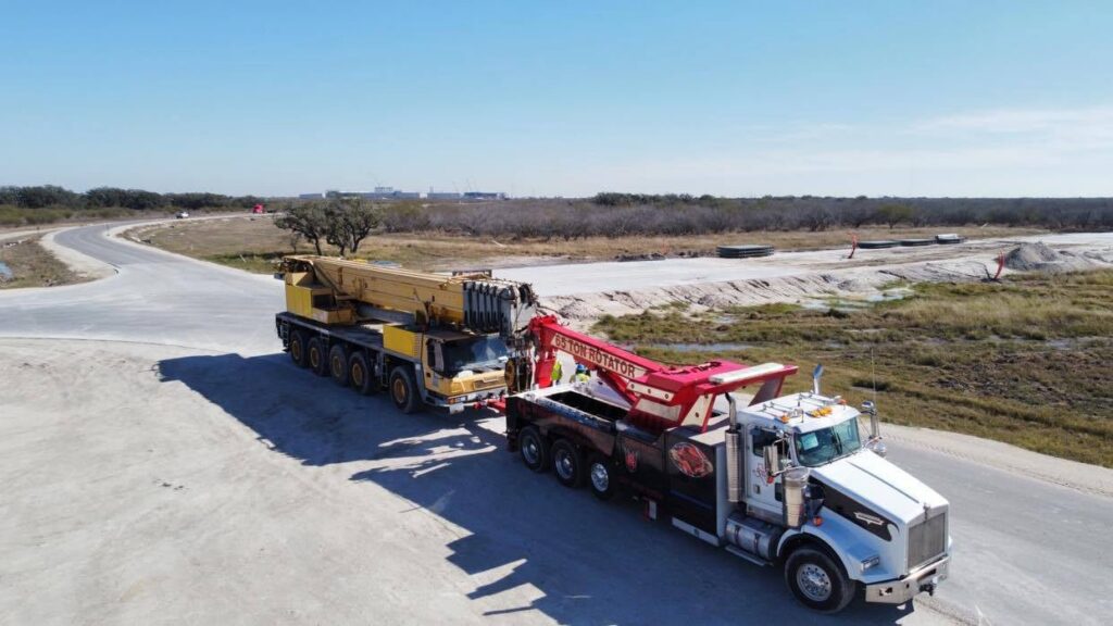 A CC Wrecker Service rotator truck performing heavy-duty towing of a large crane truck in Corpus Christi, TX.
