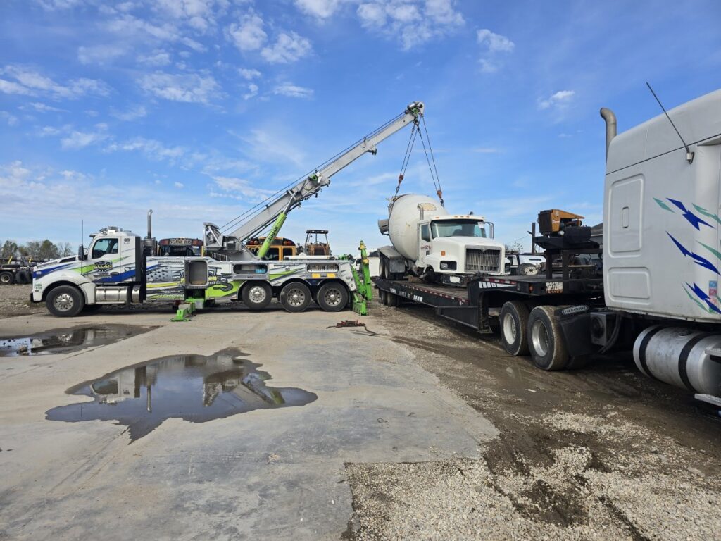 A heavy-duty wrecker from Allan Motors & Wrecker Service LLC lifting a cement mixer truck onto a trailer in Houston, TX