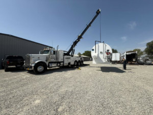 A heavy-duty wrecker from NEATS Towing & Repair LLC using its crane to lift large industrial equipment in Jonesboro, AR.