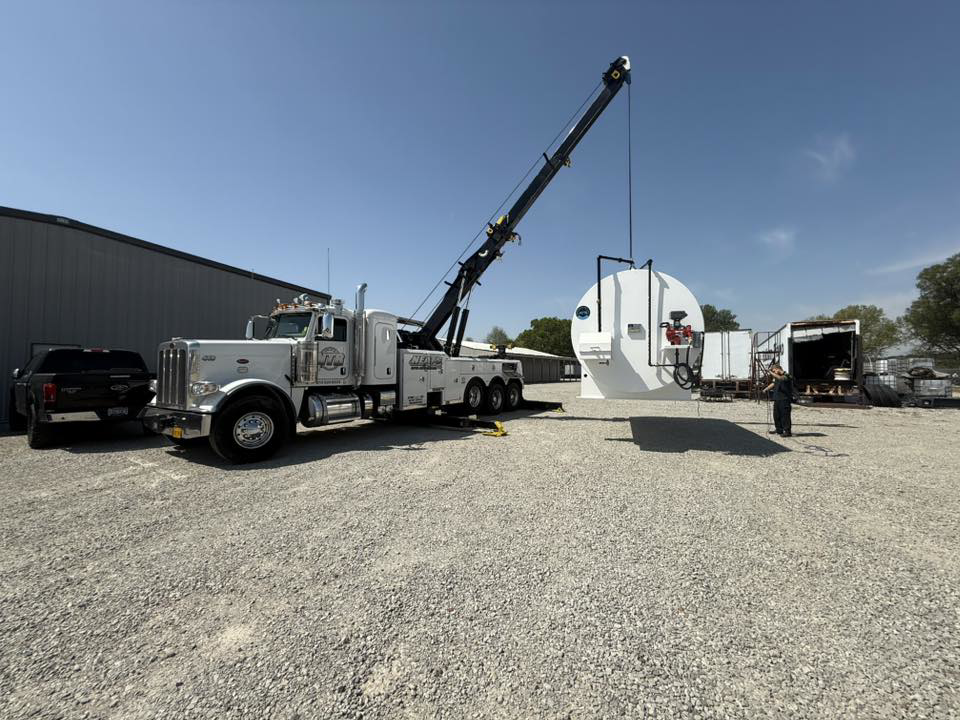 A heavy-duty wrecker from NEATS Towing & Repair LLC using its crane to lift large industrial equipment in Jonesboro, AR.