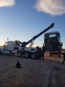 A heavy-duty wrecker from Gama Towing LLC lifting the cab of a semi-truck during a recovery operation in Carlsbad, NM.
