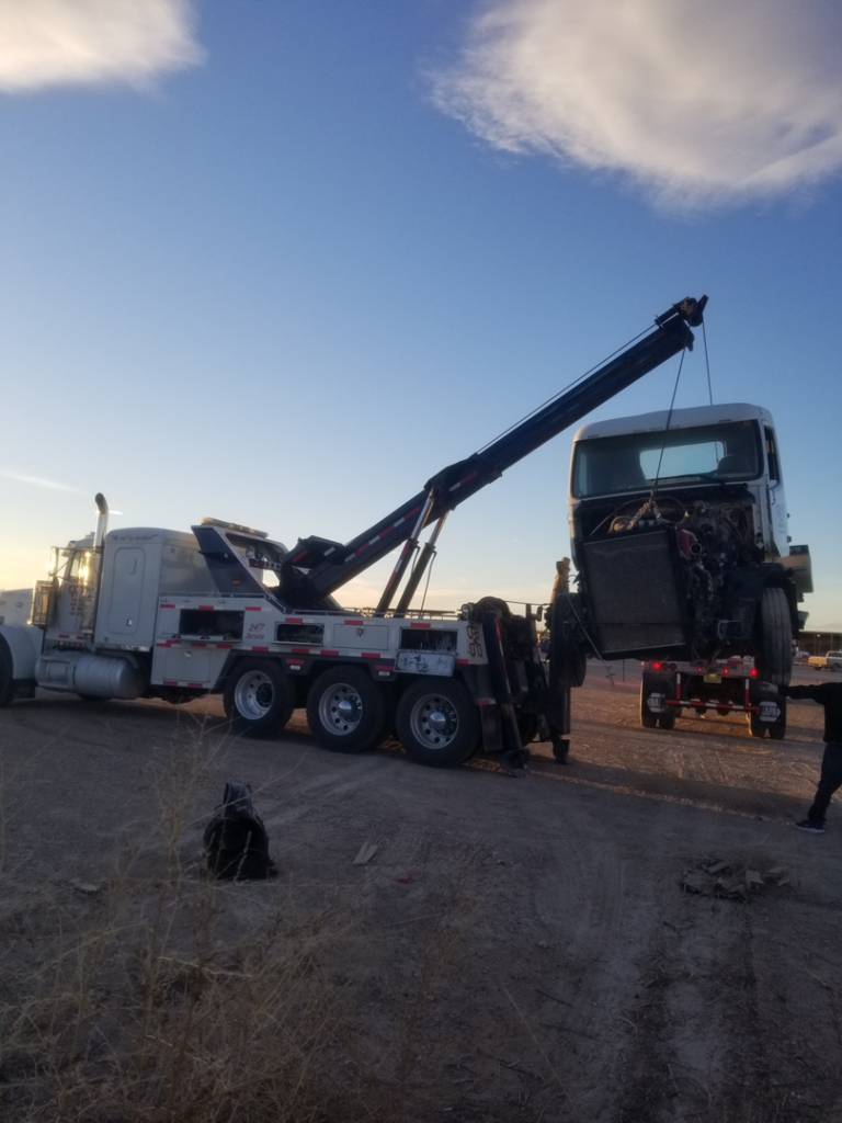 A heavy-duty wrecker from Gama Towing LLC lifting the cab of a semi-truck during a recovery operation in Carlsbad, NM.