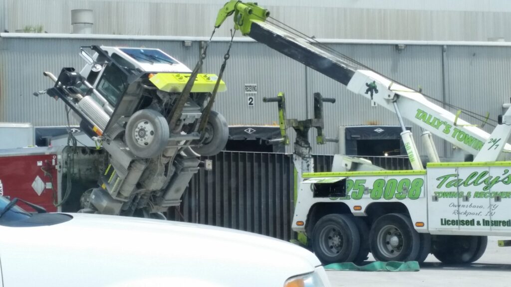 A green and white heavy-duty wrecker from Tally's Towing and Recovery lifting a truck cab in Owensboro, KY.