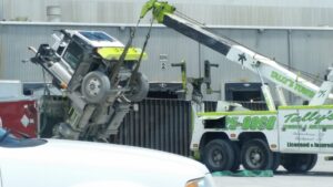 A green and white heavy-duty wrecker from Tally's Towing and Recovery lifting a truck cab in Owensboro, KY.