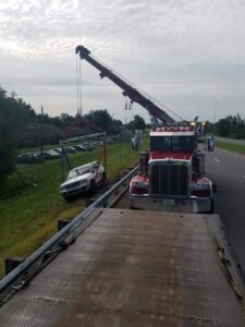 A red heavy-duty wrecker from Tally's Towing and Recovery recovering a white SUV from a ditch next to a highway in Owensboro, KY.