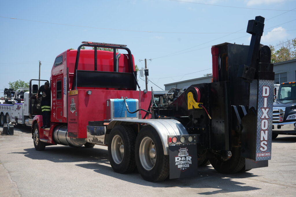 A red heavy-duty wrecker tow truck parked at Dixon's Towing & Roadside Assistance in Dallas, TX.