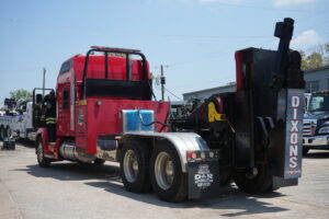 A red heavy-duty wrecker tow truck parked at Dixon's Towing & Roadside Assistance in Dallas, TX.