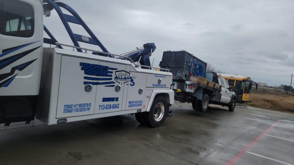 A heavy-duty wrecker from Allan Motors & Wrecker Service LLC towing a flatbed truck carrying a dumpster in Houston, TX