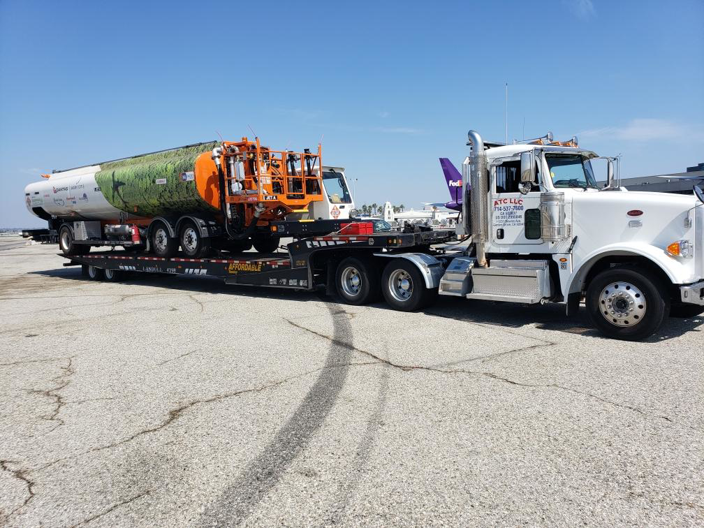 A heavy-duty tow truck from Affordable Towing LLC transporting a large tank and equipment on a flatbed trailer in Anaheim, CA.