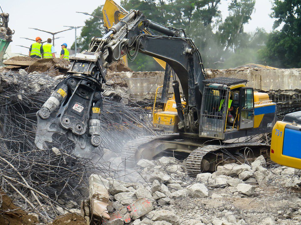 A heavy excavator with a concrete crushing attachment performing demolition for San Antonio Demolition Pros in San Antonio, TX.