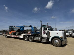 A heavy-duty tow truck hauling a Genie boom lift on a lowboy trailer for Southern Maryland Towing in Prince Frederick, MD.