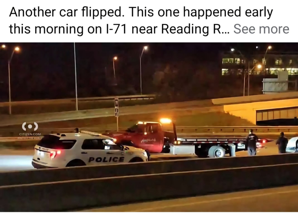 A Hopkins Towing flatbed truck with flashing lights at an accident scene on a highway at night in Cincinnati, OH.