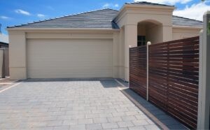 A house with a beige garage door and paved driveway, showcasing installation by Up & Down Garage Doors in Bridgeport, CT.