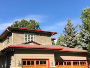 A house featuring brown horizontal siding with contrasting red trim and gutters, completed by Urban Exteriors LLC in Lakewood, CO.