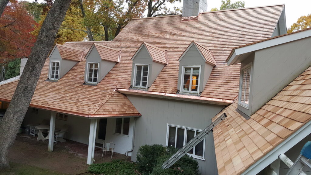 A house featuring natural cedar shake siding and roofing, indicating a recent project by JM Roofing & Siding in Rogers, AR.