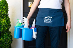 A professional house cleaner from The Cleaning Authority - Bowie, MD, carrying a caddy full of cleaning supplies.