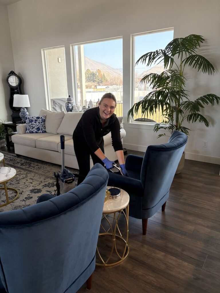 A Kleen Slate house cleaner wearing blue gloves, meticulously cleaning an armchair in a bright living room in Shakopee, MN.