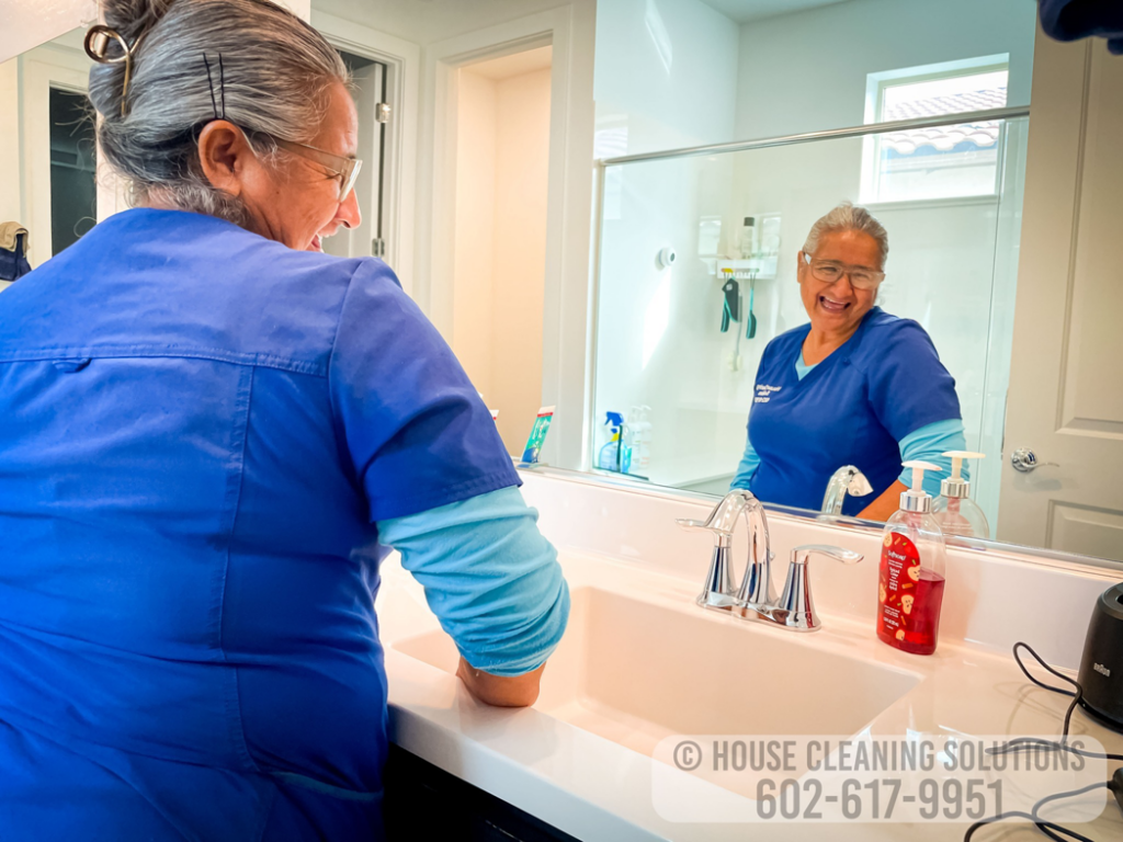 A house cleaner from House Cleaning Solutions in Mesa, AZ, is diligently cleaning a bathroom sink.