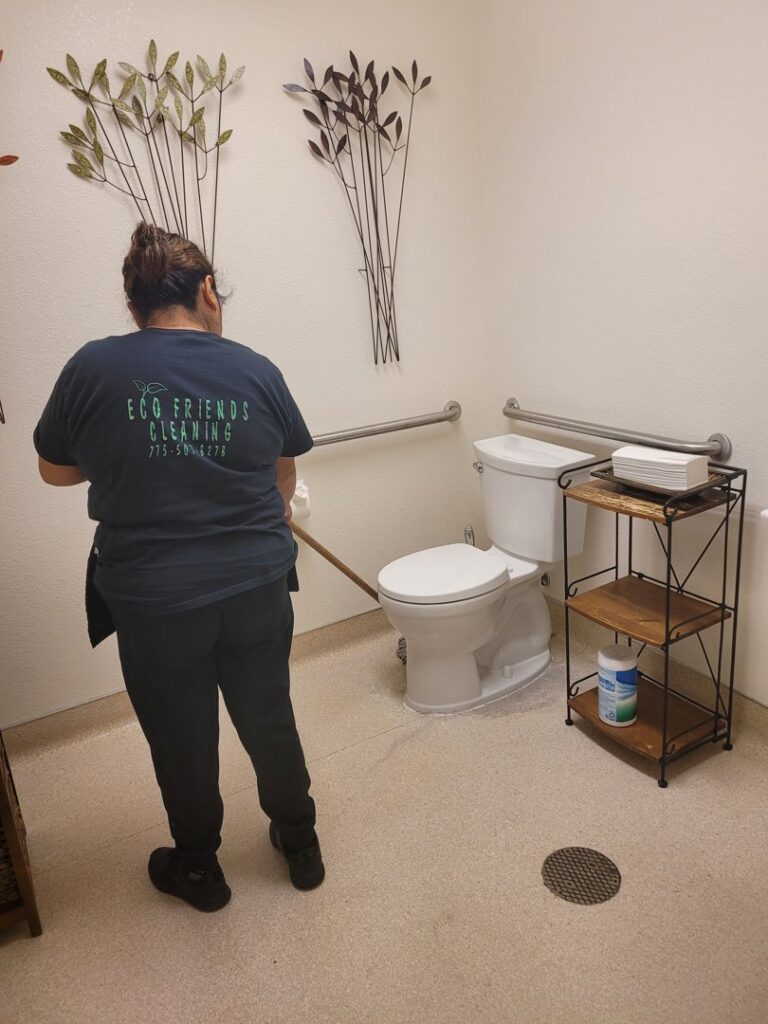 A professional house cleaner from ECO Friends cleaning service meticulously cleaning a bathroom toilet in Carson City, NV.