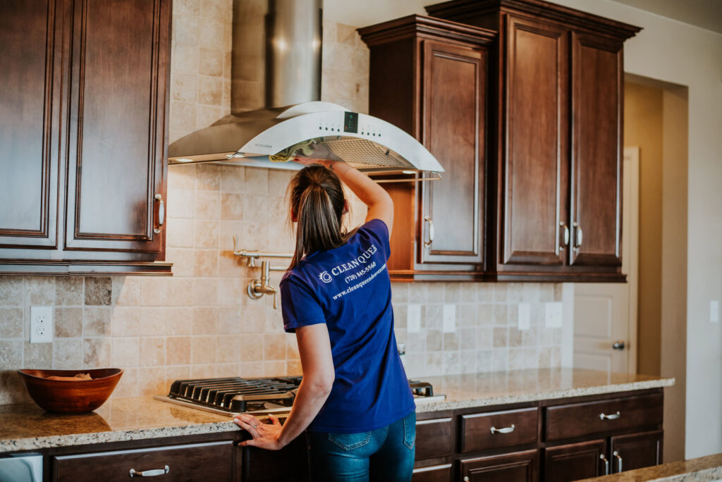 A house cleaner from Clean Queen House Cleaning meticulously cleaning a kitchen range hood in Arvada, CO.
