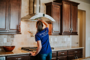 A house cleaner from Clean Queen House Cleaning meticulously cleaning a kitchen range hood in Arvada, CO.