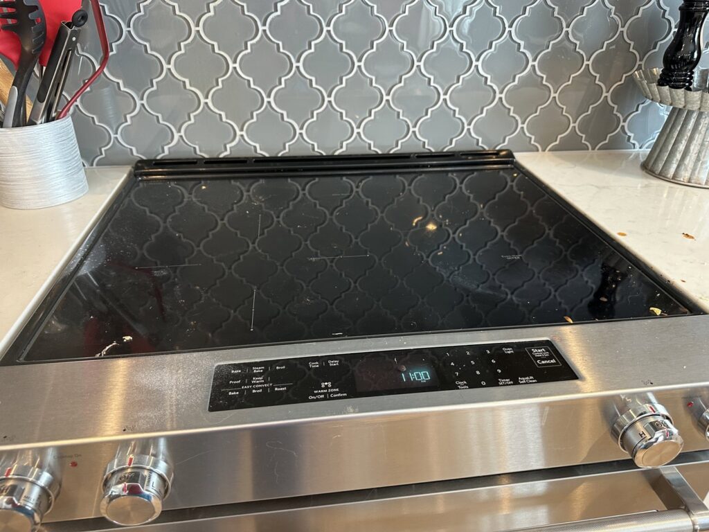 A house cleaner from J + M Cleaning, LLC in Flint, MI, actively cleaning a mirror and drawing a heart with foam.