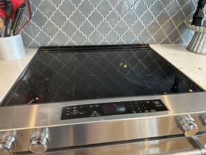 A house cleaner from J + M Cleaning, LLC in Flint, MI, actively cleaning a mirror and drawing a heart with foam.