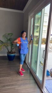 A house cleaner from Royalty Commercial & Residential Cleaning LLC cleaning a large glass sliding door in Sumter, SC.