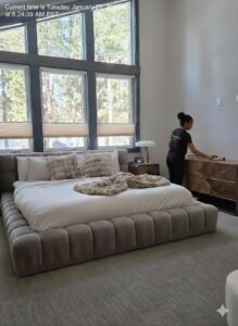 A house cleaner from ECO Friends cleaning service dusting a wooden dresser in a bright bedroom in Carson City, NV.