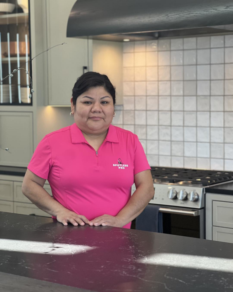A professional house cleaner from Spotless Pro Cleaning LLC in Green Bay, WI, standing in a modern, clean kitchen.
