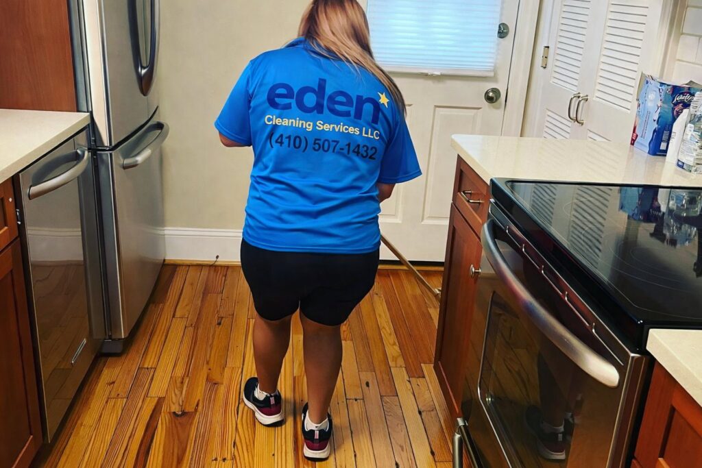 A house cleaner from Eden Cleaning Services mopping a kitchen floor in a home in Annapolis, MD.