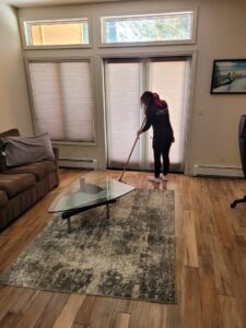 A professional house cleaner from ECO Friends cleaning service mopping a wooden floor in a living room in Carson City, NV.