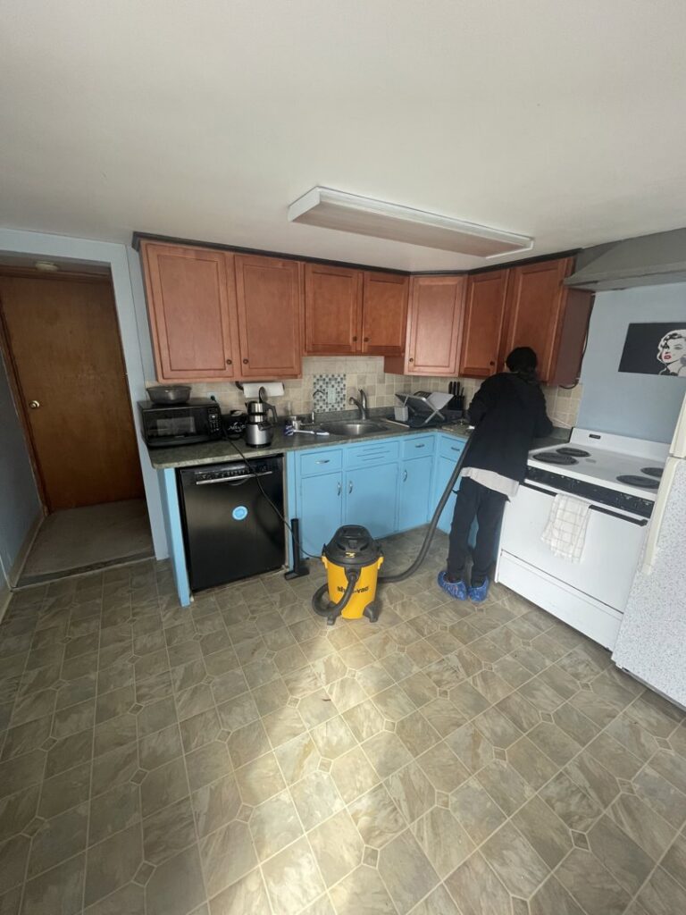 A house cleaner vacuuming a kitchen floor for North Star Cleaning in Fall River, MA.