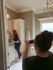 A house cleaner wiping down a bathroom mirror with a yellow cloth at Platt Cleaning Services in Lafayette, LA.