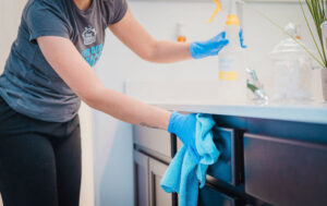 A house cleaner from Five Stars Cleaning Services wiping a bathroom vanity in West Valley City, UT.